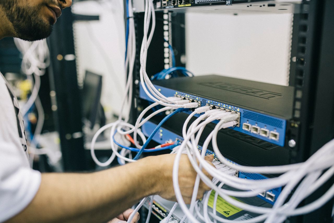 Services An IT professional configuring network cables in a server rack, focusing on Ethernet connections.